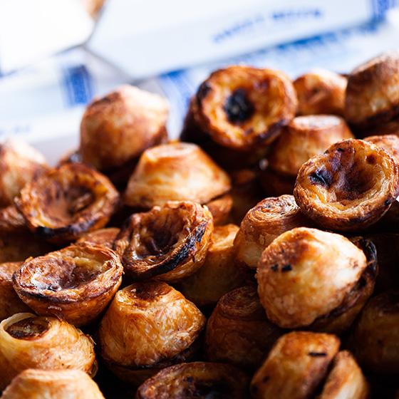 A close up image of a table piled high with Portuguese tarts